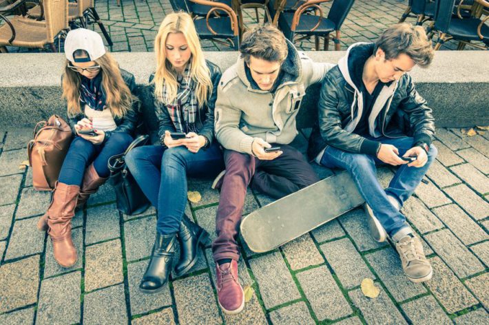 Gruppe von jungen Hipstern, die ihr Smartphone benutzen